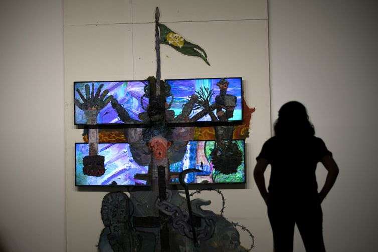 Joedson Alves/Agencia Brasil Brasilia 07/02/2023 - Uma mulher é vista em silhueta observando a obra sobre drywall e quatro monitores de TV da série Teatro Nagô Cartesiano. A cruz que penetra Pindorama, do artista, Thiago Martins de Melo, na Exposição Brasil futuro